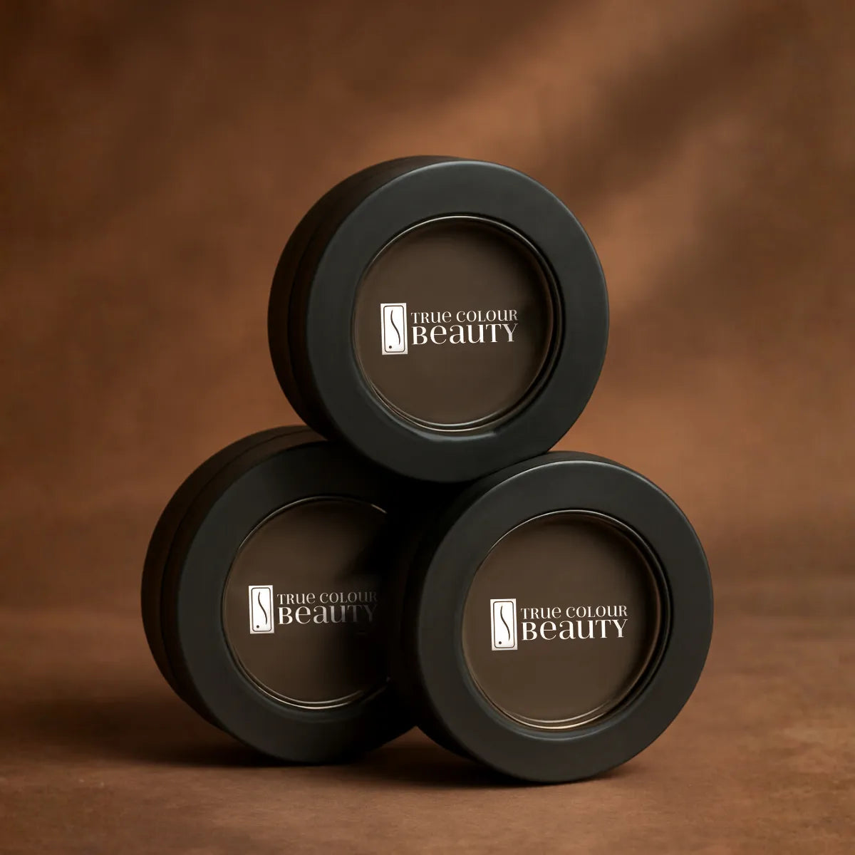 Three black containers with 'True Colour Beauty' logo on a brown background