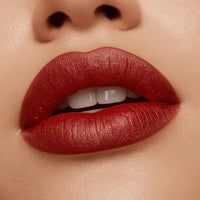 Close-up of a person's lips with red lipstick on a neutral background
