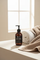 Bottle of 'Soft Skin' body wash on a bathroom counter with a white tiled wall background.