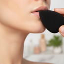 Person applying makeup with a black sponge applicator.