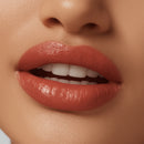 Close-up of a person's lips with a glossy red lipstick on a neutral background