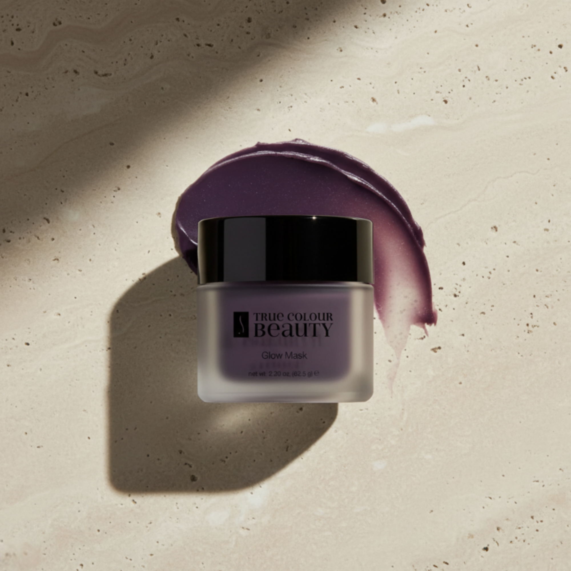 Jar of True Colour Beauty Glow Mask with a swatch on a textured beige background