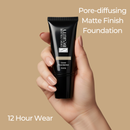 Hand holding a black foundation tube with beige background