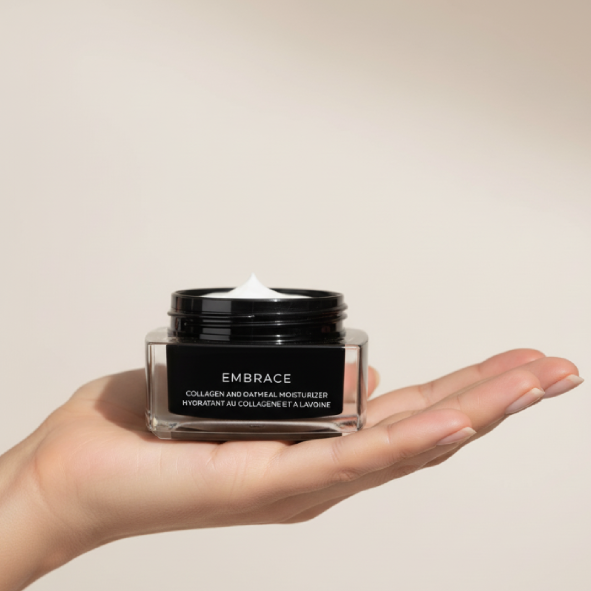 Hand holding a jar of 'Embrace' moisturizer against a beige background
