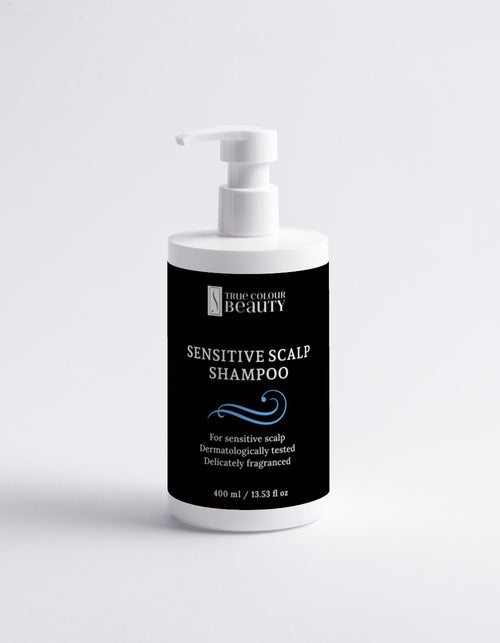 Bottle of sensitive scalp shampoo with a black label on a white background