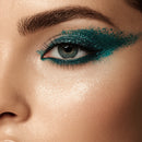 Close-up of a woman's eye with teal glittery eyeliner