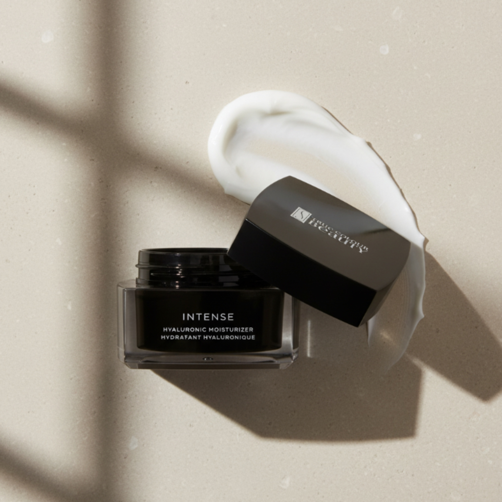 Black skincare jar labeled 'Intense' with a white cream on a beige background