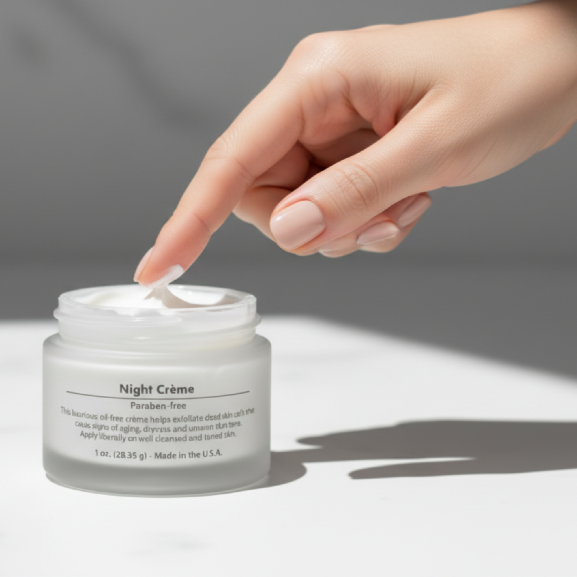 Hand applying night cream from a jar labeled 'Night Crème' on a neutral background