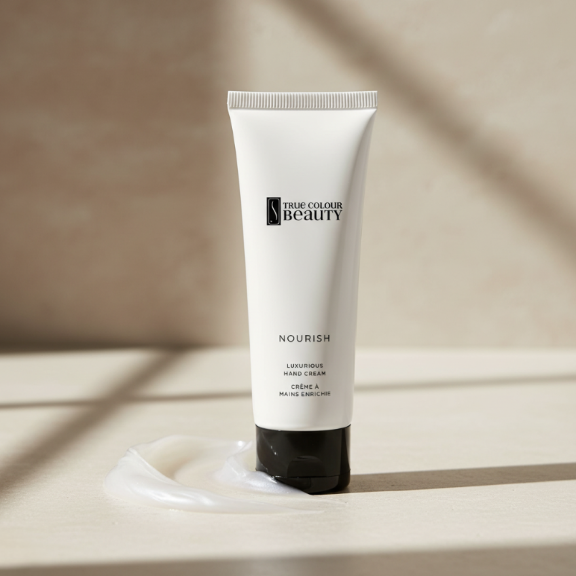 Tube of True Colour Beauty hand cream on a beige surface with soft shadows