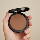 Hand holding a compact powder with a neutral background