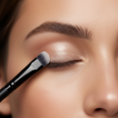 Close-up of a person applying makeup with a brush to their eyelid.