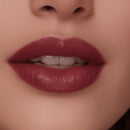 Close-up of a woman's lips with a dark pink lipstick on a neutral background