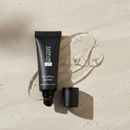 Black lip balm tube on a beige surface with 'True Colour Beauty' branding