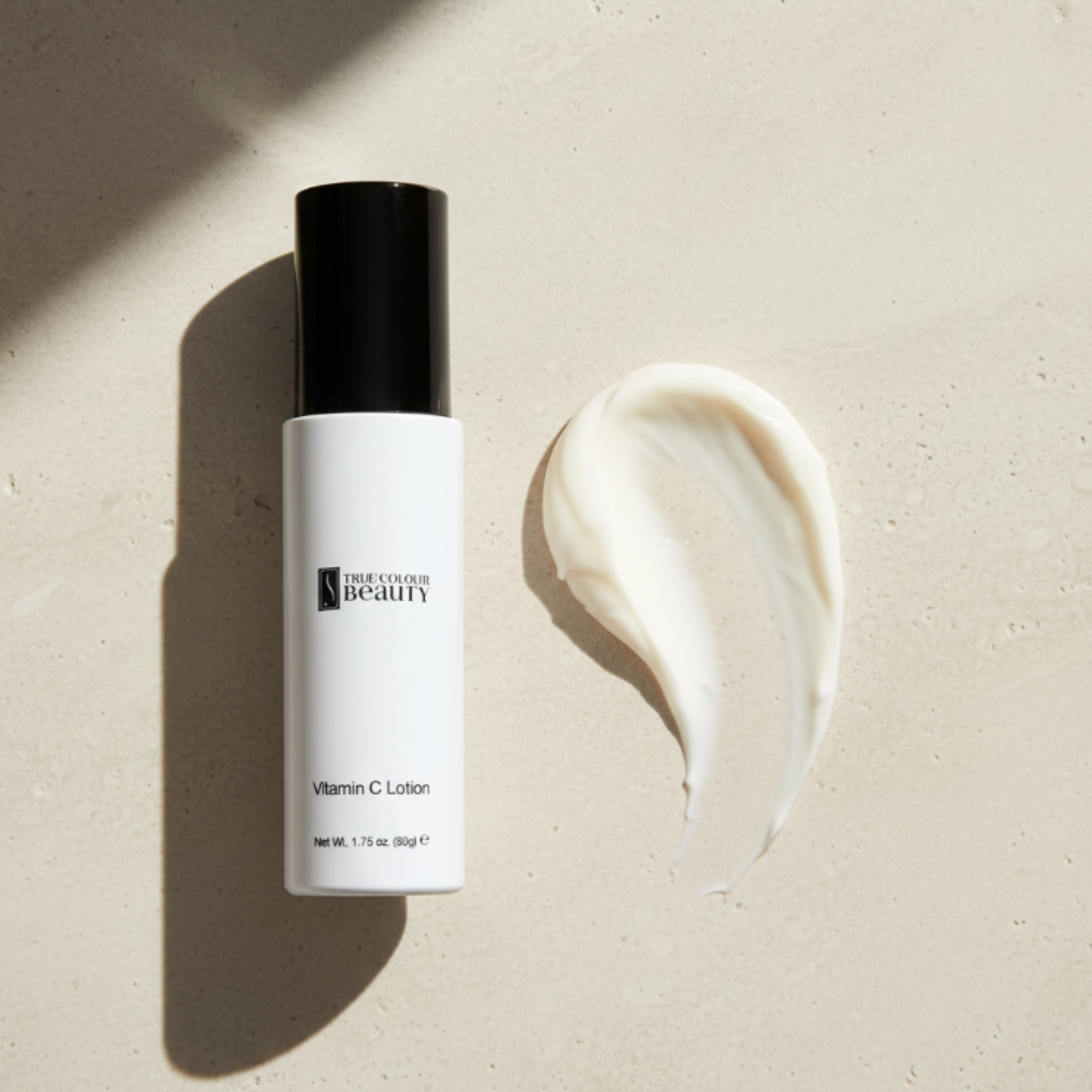 Vitamin C lotion bottle with a swatch of cream on a beige background