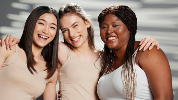 Three women with diverse skin tones smiling with glowing skin