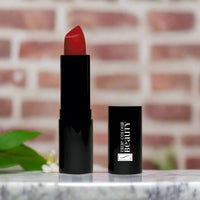 True Colour Beauty's Glamorous Red Luxury Lipstick on a marble counter-top with a red brick wall background.