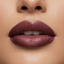 Close-up of a woman's lips with a mauve lipstick on a beige background