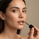 Woman applying lip gloss with a neutral background