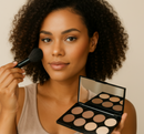 Woman applying makeup with a brush and a palette on a beige background